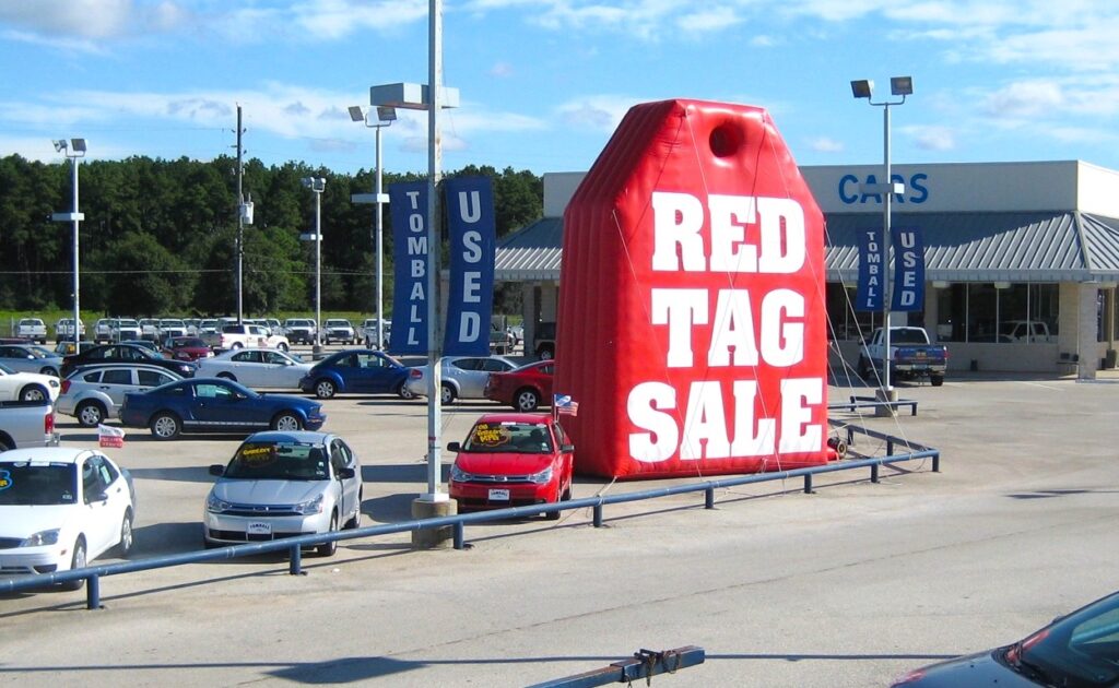 red sale inflatable in front of automotive dealership